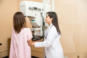 Doctor helping patient get a mammogram