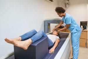 Healthcare worker preparing woman for bone density scan