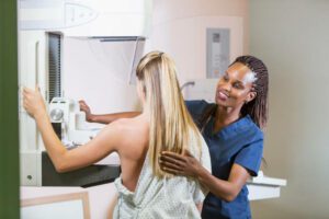 woman getting a mammogram helped by an African-American nurse