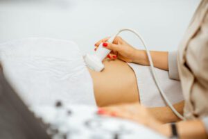 Doctor performs ultrasound examination of a women's pelvic organs or diagnosing early pregnancy at the medical office. Close-up view with no face