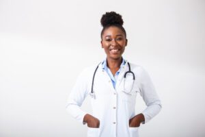 Internal Medicine Doctor with a stethoscope, hand in her pocket. Close-up of a female smiling while standing straight on white background