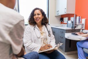 Empathetic female primary care doctor listens to unrecognizable boy