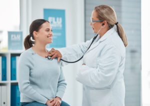 primary care doctor examining a patient with a stethoscope during a consultation