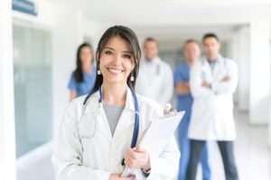 Happy Latin American doctor with medical staff at the ER of a hospital - healthcare and medicine