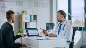 Family Medical Doctor is Explaining Diagnosis to a Young Male Patient