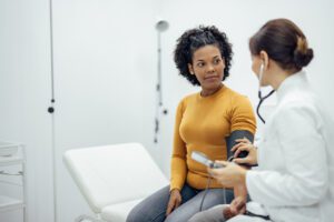 Primary care Doctor measuring blood pressure to a smiling woman