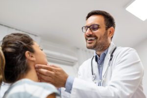 primary care doctor checking patient's tonsils at hospital.