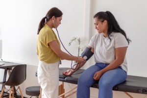 Woman having blood pressure measured by doctor in preventive health care center