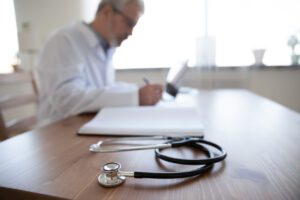 general Practitioner writing on his notepad during consultattion