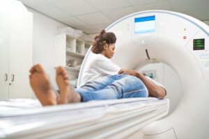 Female doctor assisting male patient while doing MRI scan in medical examination room